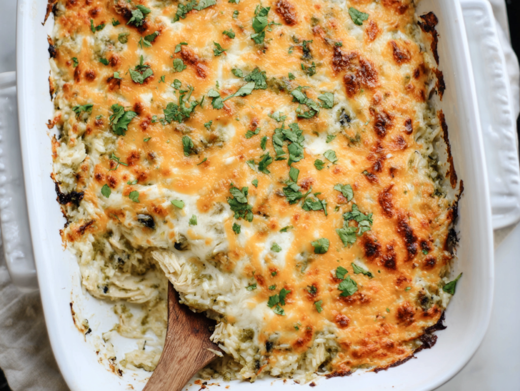 salsa verde chicken and rice bake in a white ceramic dish with melted cheese on top, top-down view